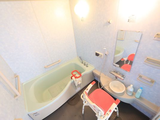 施設の写真 個浴用浴室が用意されている。白い壁にカーブを描いた浴槽がある。床は滑り止めの効いた素材でできている。