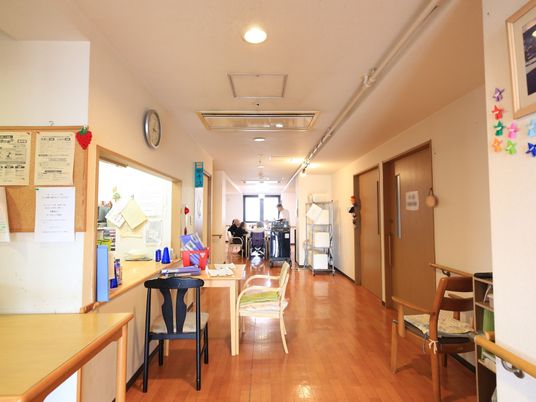施設の写真 エントランスから施設内を見た図である。左手に事務所へ続く受付がある。カウンターの前に椅子がある。