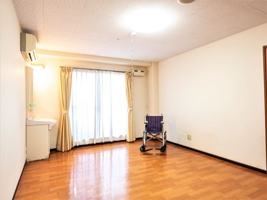 施設の写真 居室を別の角度から撮った写真である。大きな窓の左側に洗面台があり、その上にエアコンを設置。