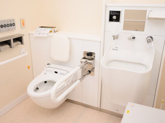 バリアフリーの浴室設備 トイレ 手すりがついたトイレと洗面台がきれいに並び、清潔感のある空間です。利用者の身体状況に配慮した設計が施されています。