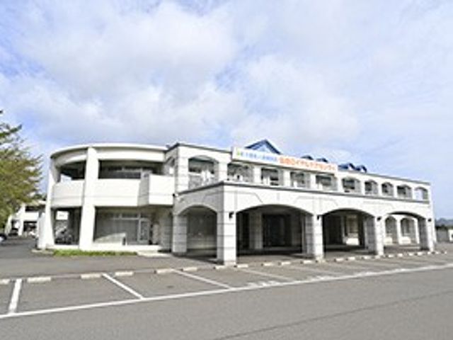 施設外観 外観   白い外壁にアーチ状の出入口が並ぶ、落ち着いた雰囲気の建物です。駐車スペースも見えて、来訪しやすい印象があります。