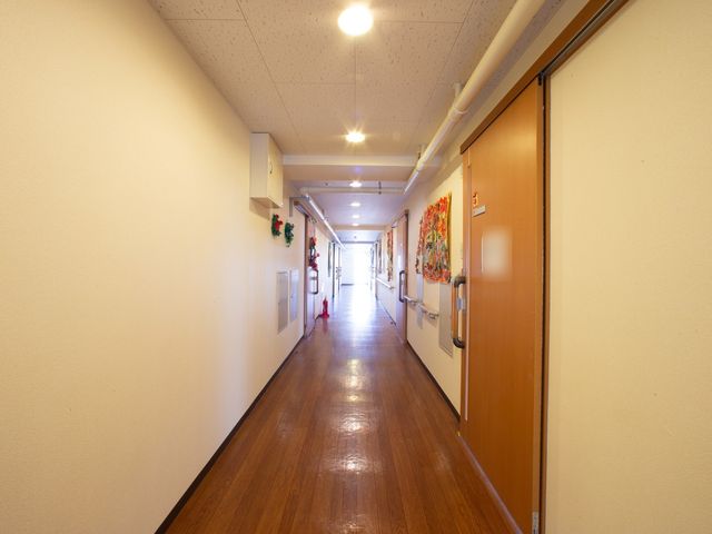 廊下の明るい風景 通路 手すりが備え付けられた清潔感あふれる廊下です。装飾された壁が温かみのある雰囲気を演出しています。