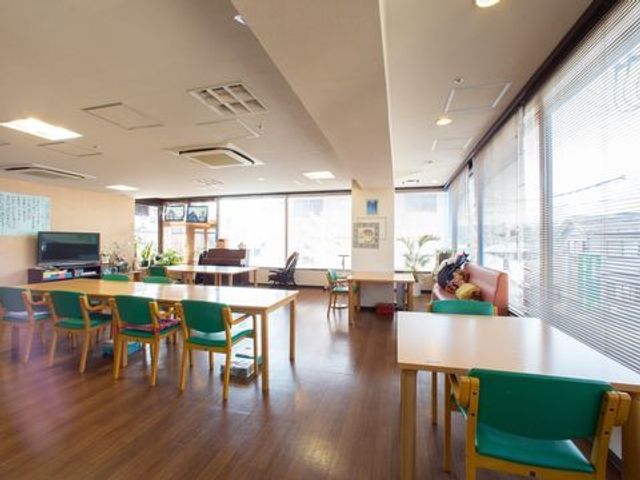 共有ラウンジの明るい風景 食堂 広々とした明るい共有ラウンジです。木目調の床や爽やかな光が差し込む窓辺で、共同生活のリラックスした時間を過ごせます。