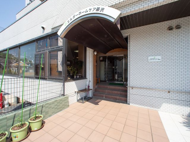 エントランスの明るい外観 玄関 手入れが行き届いた植物が迎える入り口は開放感があり、訪れる方々へ清潔感を提供しています。車椅子の方も安心して利用できるバリアフリー設計です。