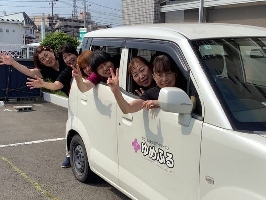 送迎車から手を振るスタッフたち  