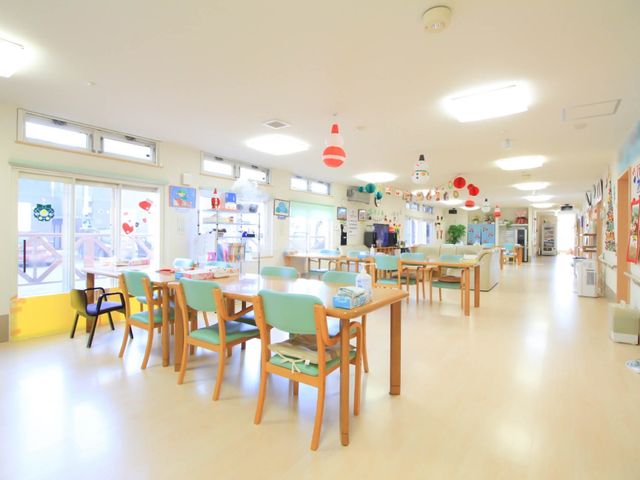 明るいデイルーム リビング 広々とした明るい食堂では、風通しの良い大きな窓と色鮮やかな装飾が心地よい空間を提供しています。様々なレクリエーションも楽しめるように工夫されています。