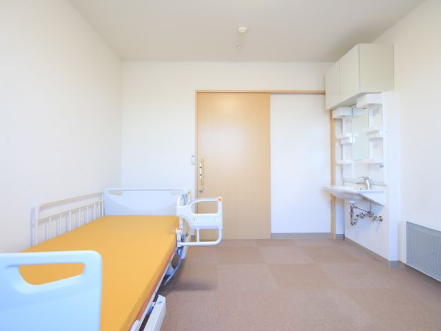 居室のベッドと洗面台 居室 清潔感あふれる個室で、明るい日差しが差し込む快適な空間が広がっております。身の回りのお世話がしやすいように、洗面台も設置されています。