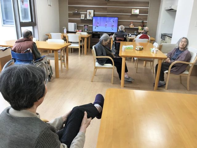 リビングにいる人々 リビング ゆったりとしたリビングで、居住者がテレビを観たり、くつろいだりしています。明るく開放感のある空間が特徴です。
