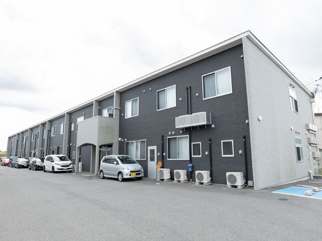 灰色の建物の外観 外観 ゆったりとした駐車スペースのある施設外観です。働く環境を大切にされる方にも適しています。