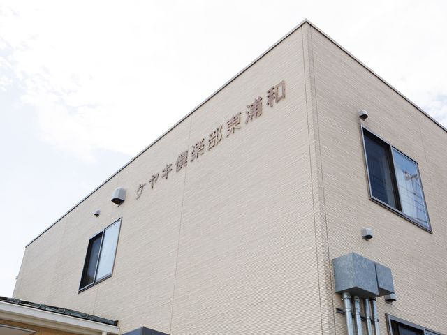 明るい外観の建物正面 外観 落ち着いた色合いの建物が、働く環境の快適さを予感させます。現代的なデザインは、訪れる人たちを温かく迎え入れます。