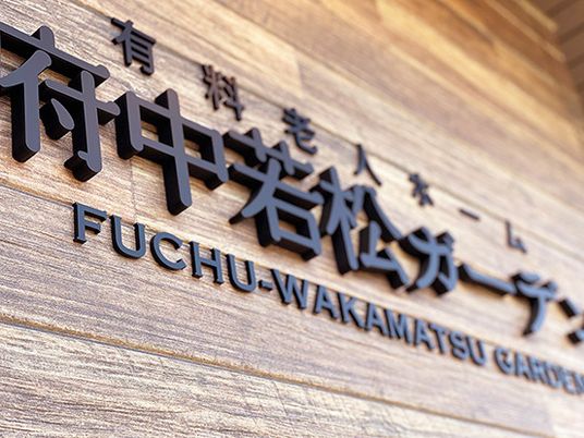 木目調の壁に掲げられた施設名看板