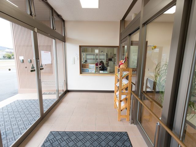 明るいエントランス風景 玄関内部 自動ドアを備えた広々としたエントランスです。スタッフが作業に集中している落ち着いた雰囲気が伝わります。