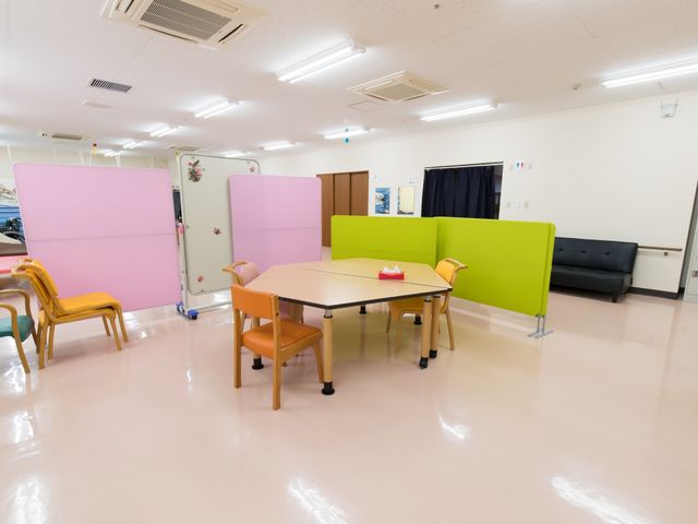 多目的室の明るい空間 多目的ホール カラフルな仕切りが特徴の多目的室です。設えられたテーブルはご利用者のコミュニケーションの場となっています。