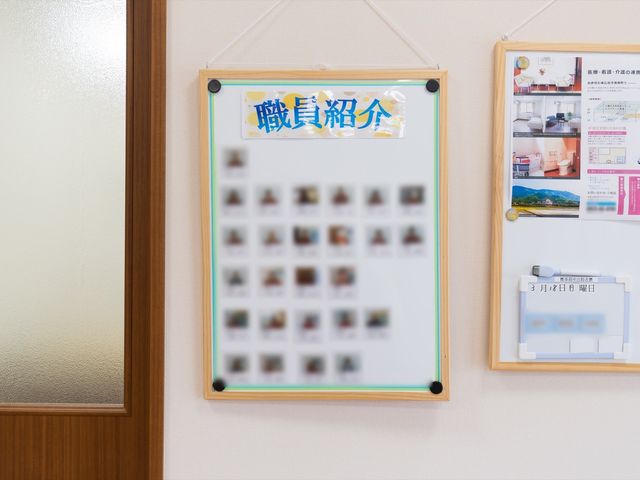 掲示物と壁面の様子 職員紹介 壁に掲示された情報板が見やすい場所に配置されており、施設の日々の活動や情報が共有されている様子が伺えます。