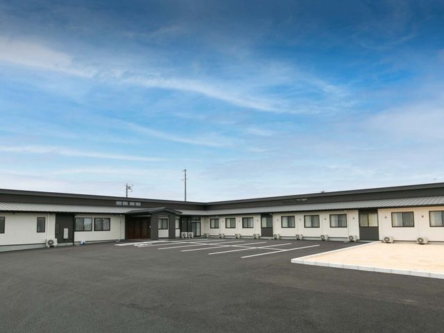 平屋建ての建物外観 外観 広々とした駐車スペースが確保された平屋建ての施設です。天気の良い日には青空が映えます。