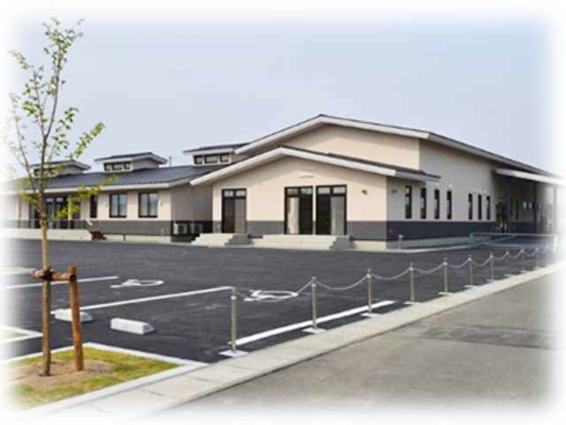 平屋の施設外観 外観   落ち着いた色合いの平屋建てで、出入りしやすい建物に見えます。広い駐車スペースもあり、働く方の車の利用にも便利そうです。