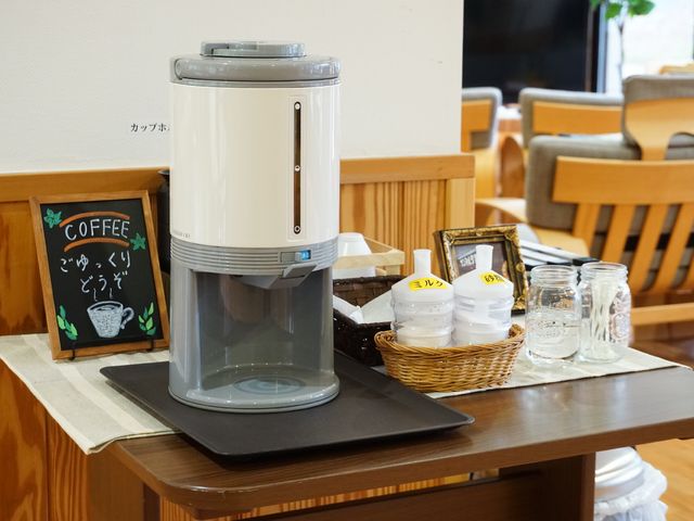 ウォーターサーバーとコーヒー看板 共有スペース 明るく広々とした飲み物コーナーでは、いつでも新鮮な水や温かい飲み物をご自由にお取りいただけます。