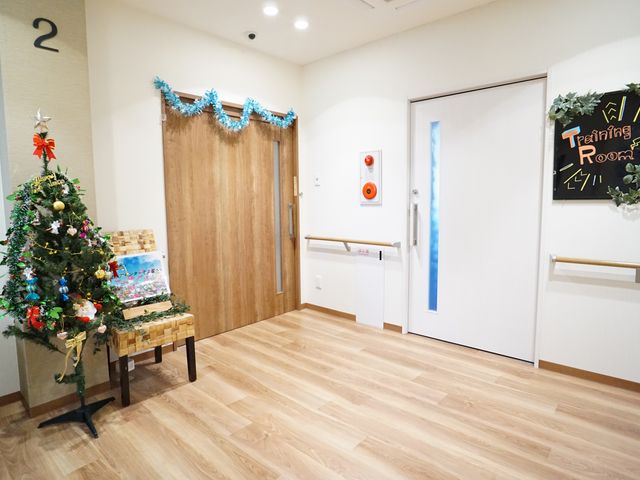 クリスマスツリーのある廊下 廊下 季節の飾り付けが施された廊下は、温かみのあるデザインで訪れる人々を迎えます。機能訓練室への案内も視認しやすいです。
