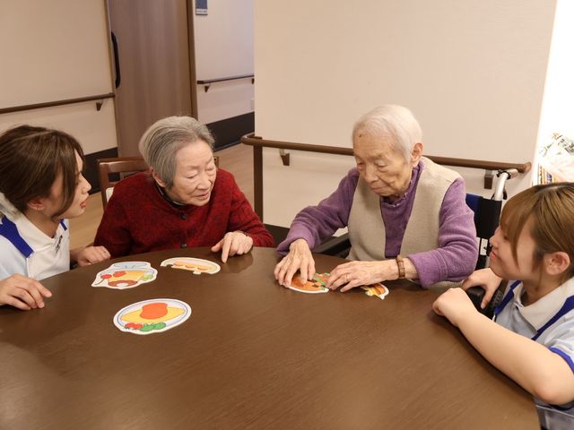 交流するテーブル 多目的室 利用者とスタッフが和やかに会話を楽しむ、多目的な交流空間です。自然な対話が仕事の一環です。
