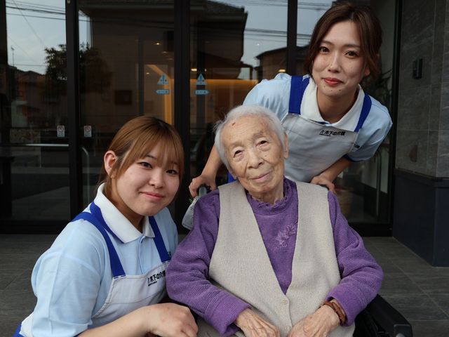 車椅子利用の様子 エントランス エントランスで、スタッフが穏やかに利用者をサポートしています。温かい雰囲気が感じられます。