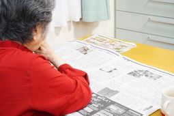赤い服の女性が新聞を読む