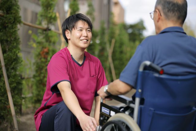 会話する介護スタッフと利用者の庭  