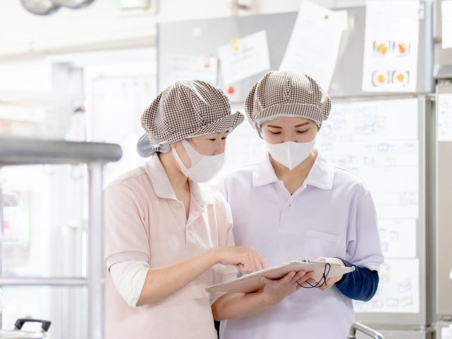 スタッフの様子キッチン キッチン 職員がメモを確認しながら、一緒に作業を進めています。チームワークが大切にされています。