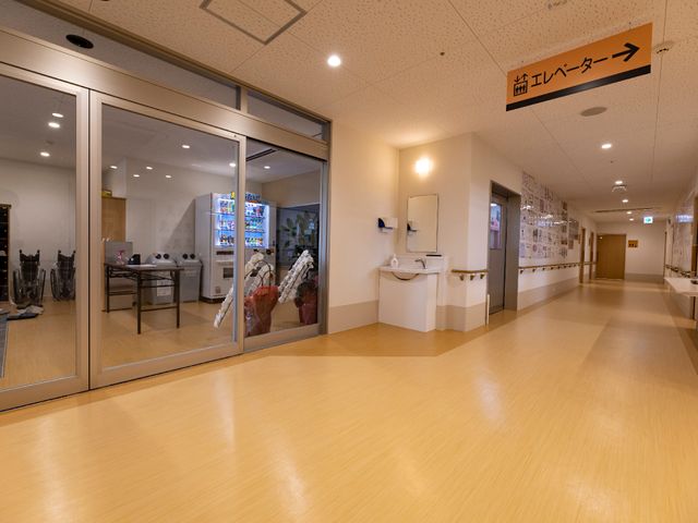 明るく広々とした廊下 廊下 床が明るく清潔感のある廊下には、安全な歩行をサポートする手すりが設置されています。周りにはレクリエーション用の空間もあり、穏やかな日々を過ごせる環境です。