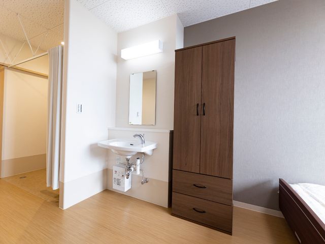 洗面台付き居室の一角 居室 ゆったりとした空間の居室で、洗面台も完備されており、個人のプライバシーがしっかりと守られています。