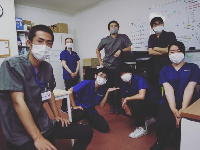 スタッフの集合 スタッフイメージ   マスクを着けたスタッフの皆さんが集まり、落ち着いた表情で写っています。連携しながら働く雰囲気が伝わります。
