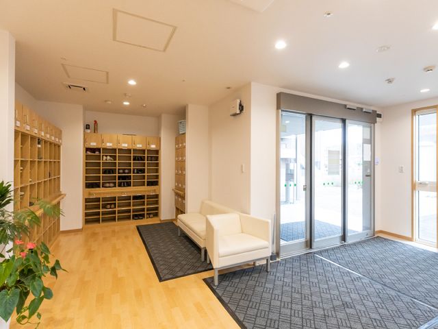 清潔なエントランスの風景 玄関 ゆったりとしたソファが配置され、安心してお過ごしいただける落ち着いたエントランスです。履物を整理できるシューズボックスが完備されており、日々の暮らしに配慮が感じられます。
