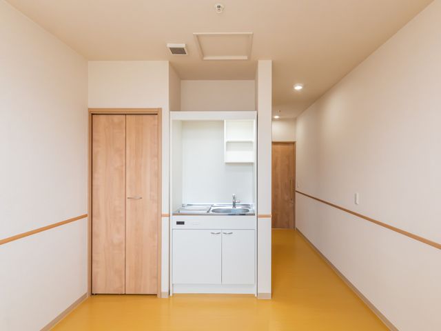 居室の洗面台付き廊下 居室 明るく落ち着いた雰囲気の居室には、日常生活に便利な洗面台が備わっています。安全に配慮された手すりも設けられ、快適な生活空間を提供しています。