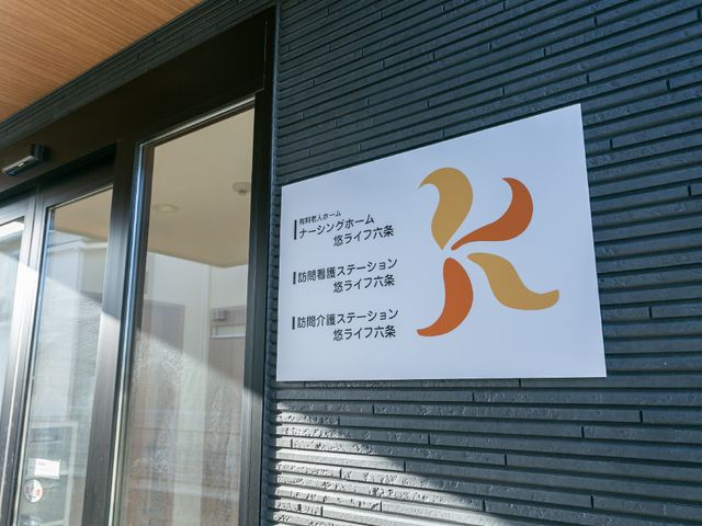 施設のシンボル看板 ロゴ 落ち着いた色合いの看板が設置された入り口です。訪れる方々への明確な案内がされています。