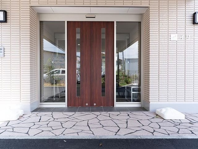 木目調のエントランス扉 エントランス 落ち着いた色合いのエントランスは訪れる人を優しく迎え入れます。広々とした開口部でバリアフリーな設計を感じられます。