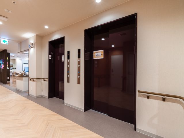 清潔な廊下とエレベーター エレベーター 手すりが取り付けられた広々とした廊下です。移動のしやすさを考えた設計で、快適な勤務環境を提供しています。