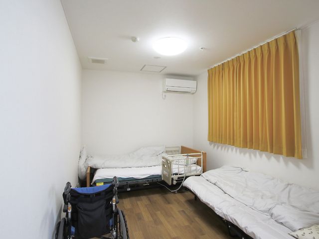 清潔な居室と車椅子 居室 整えられたベッドと車椅子が配置された部屋です。快適な生活空間の提供を心がけております。