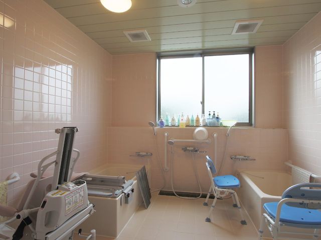 バリアフリー設計の浴室 介護浴槽 広々とした浴室には安全に配慮した椅子や手すりが整っており、快適にご利用いただけます。窓からは自然の光が差し込み、清潔感のある空間です。