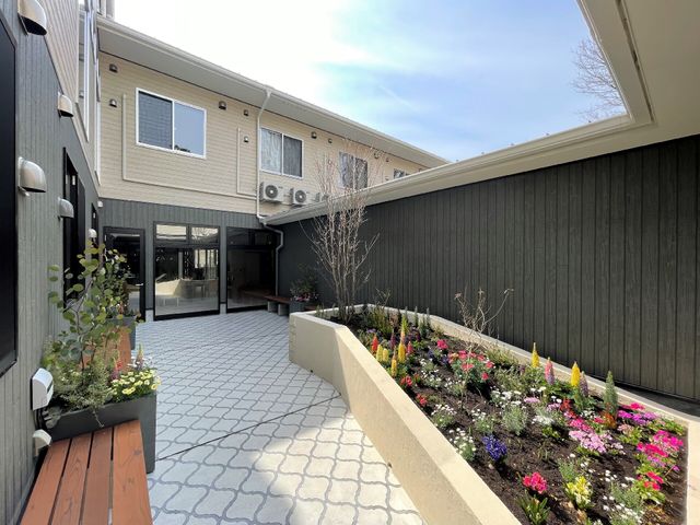 中庭に咲く花と建物 中庭 季節の花々が彩る落ち着いた中庭です。日々の憩いの場として利用者がゆったりと自然を感じられる空間になっています。