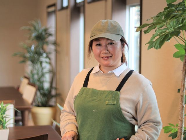 スタッフが笑顔で立つ様子 調理師 笑顔で料理を手がけるスタッフが、温かな雰囲気を創り出しております。この空間での業務は、やりがいを感じられることでしょう。