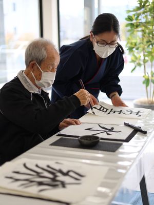 書道を楽しむ高齢者と職員