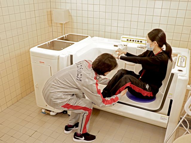 介助と共に入浴訓練 清潔で安全な浴室で、入浴介助の様子が確認できます。手厚いサポートを受けながら、快適な生活を送ることができます。