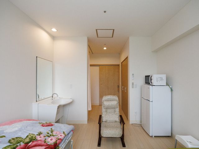 居室内設備の様子 居室 落ち着いた色合いの居室です。ベッドや冷蔵庫、そして洗面台も完備され、快適な個人空間を確保しています。