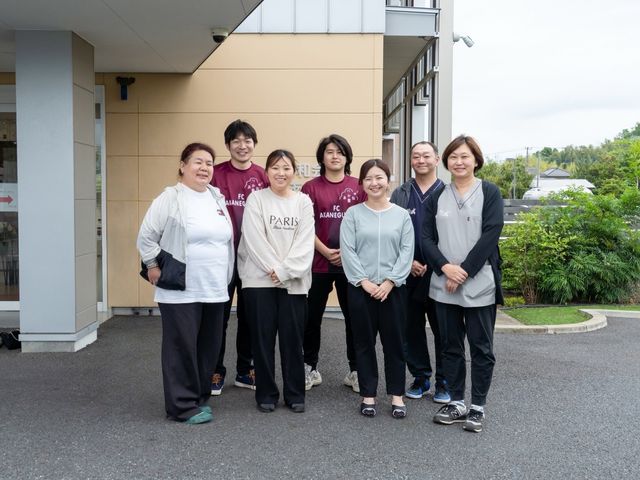 施設スタッフ集合写真 スタッフ 笑顔で並ぶスタッフが皆様をお迎えします。チームワークを大切にした温かい雰囲気の職場環境です。