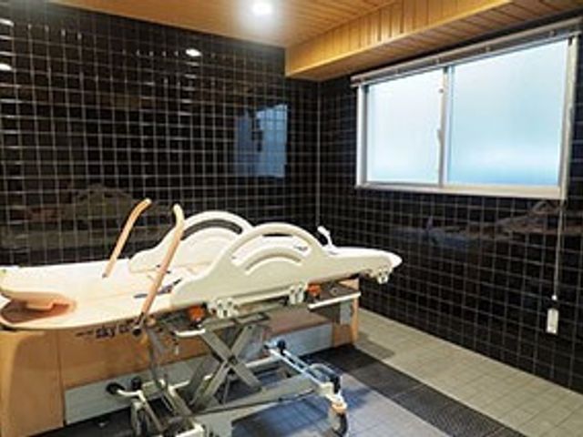 快適なケア用浴室 介護浴槽 床から天井までタイル貼りの清潔な浴室です。高齢者の安全を配慮したベッド型の入浴設備が整っています。