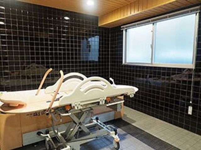 快適なケア用浴室 介護浴槽 床から天井までタイル貼りの清潔な浴室です。高齢者の安全を配慮したベッド型の入浴設備が整っています。