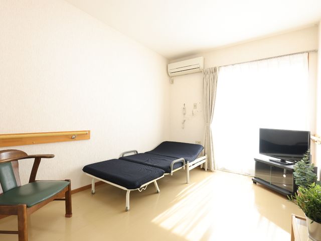 居室のベッドとテレビ 居室 清潔感のある居室です。窓からの日差しが明るく、ゆったりとした時間を過ごせる空間が広がっています。