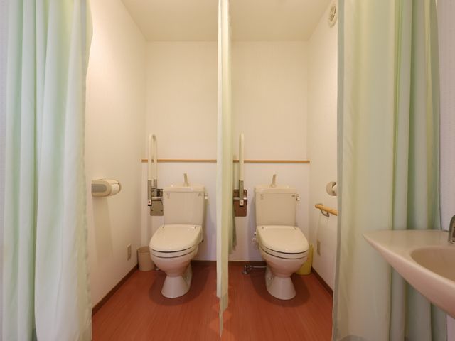 バリアフリートイレの室内 トイレ 安全に配慮されたトイレの設備で、手すりや広めのスペースがあります。スタッフや利用者の方々も安心してご使用いただける環境です。