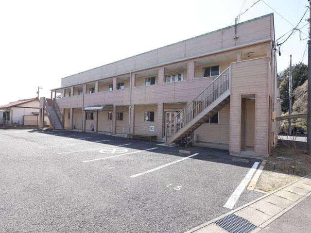 明るい空の下の建物外観 外観 ゆったりとした駐車スペースが確保された清潔感のある建物です。階段の手すりやスロープも整備され、安全に配慮された設計となっています。