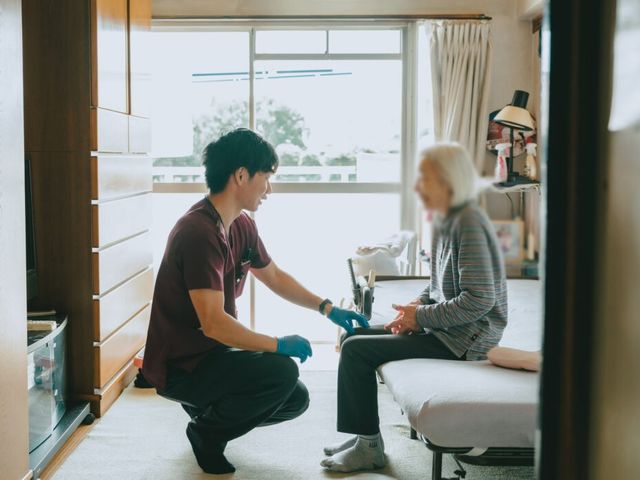 スタッフイメージ 居室 広々とした部屋で、介護士が利用者と親しげに会話をする様子です。働きやすい雰囲気が感じられます。