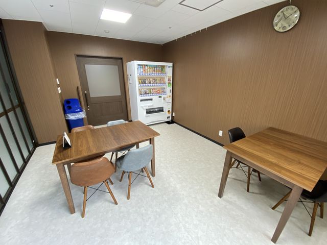 共有スペース 多目的室 ゆったりとしたテーブルが並ぶ共有のスペースです。自動販売機のある便利な角部屋で、寛ぎのひとときをご提供します。
